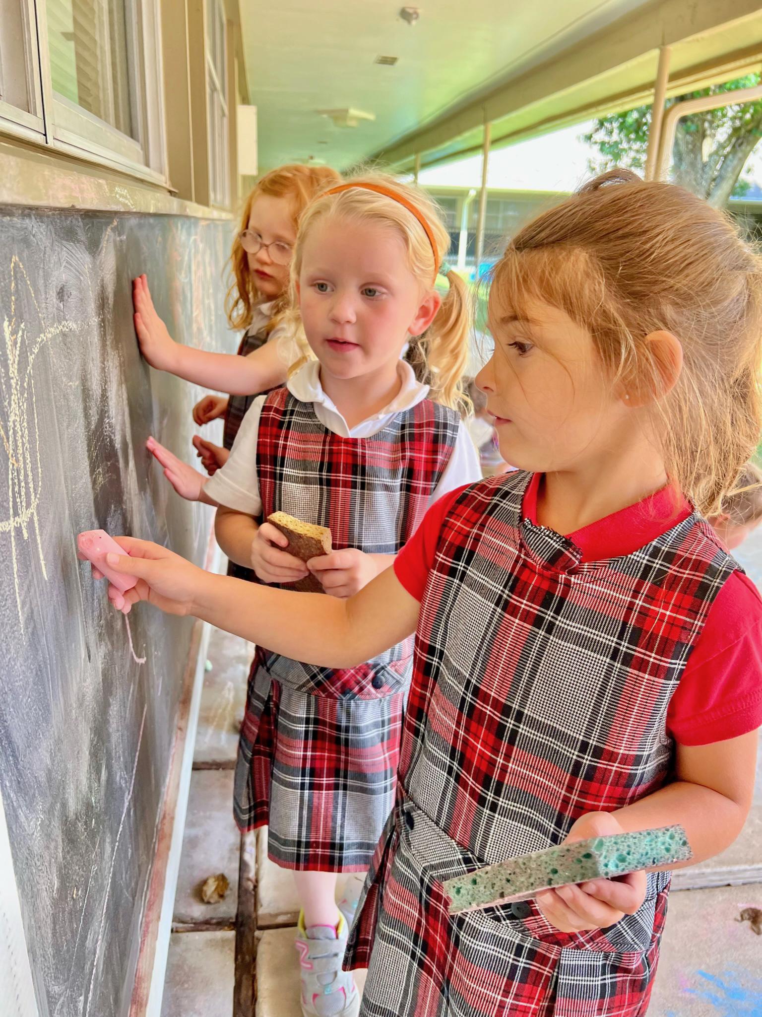 Three students drawing on a chalkboard
