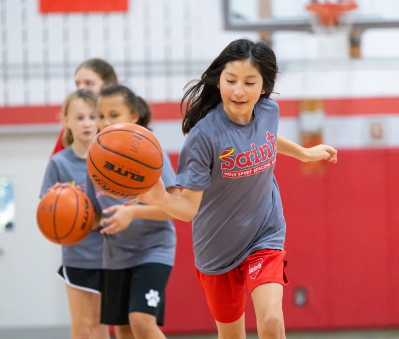 students playing basketball in gymnasium