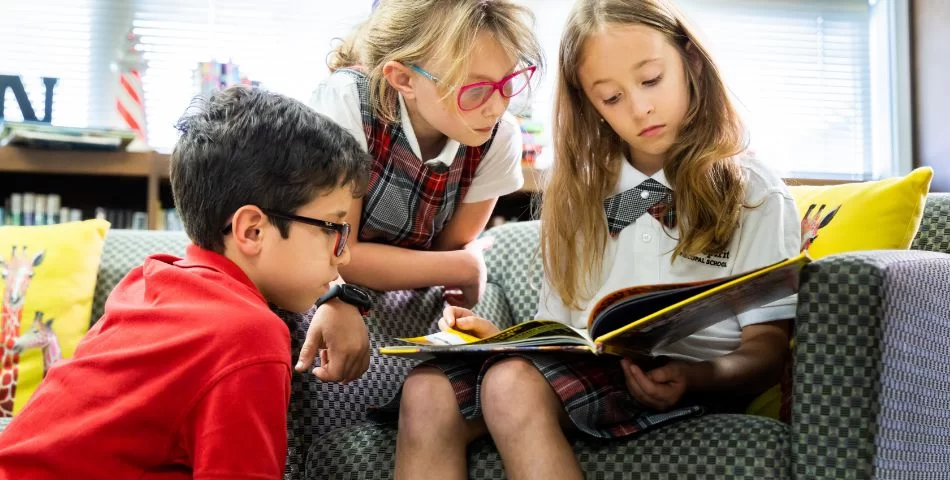 Three students reading a book