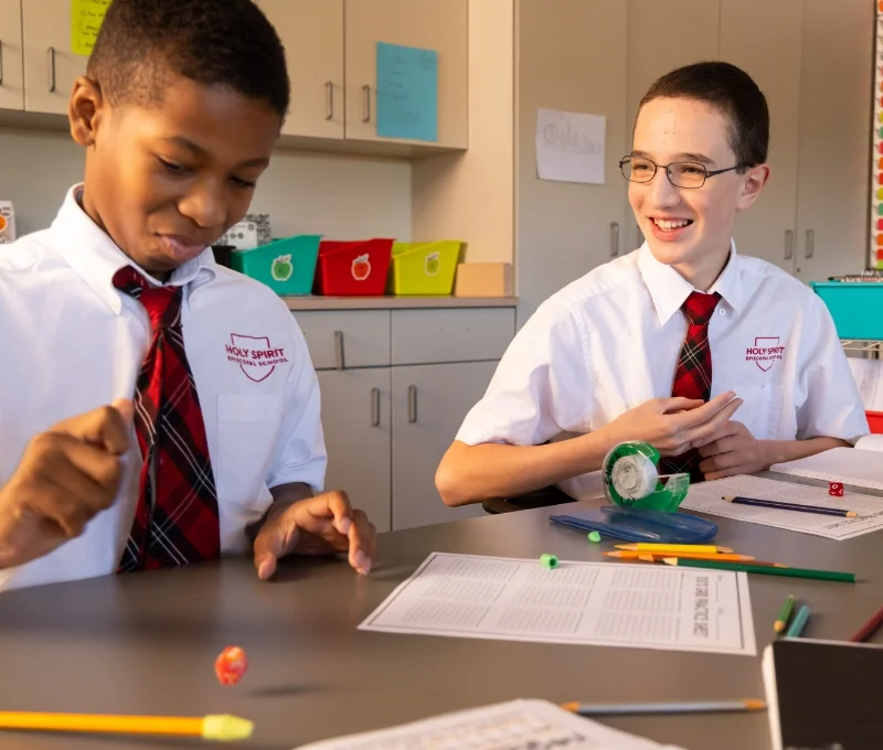 2 students sitting together in a classroom and smiling